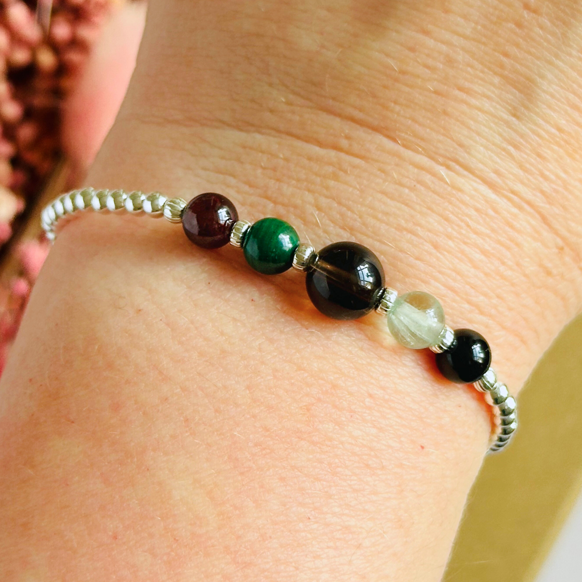 This sterling silver Capricorn bracelet is made with a selection of five healing crystals all believed to resonate with the Capricorn zodiac sign. The central bead is 8mm, the other four are 6mm. On an elasticated band of 3mm sterling silver beads with corrugated accent beads. Featuring garnet, malachite, fluorite, smoky quartz and black tourmaline.