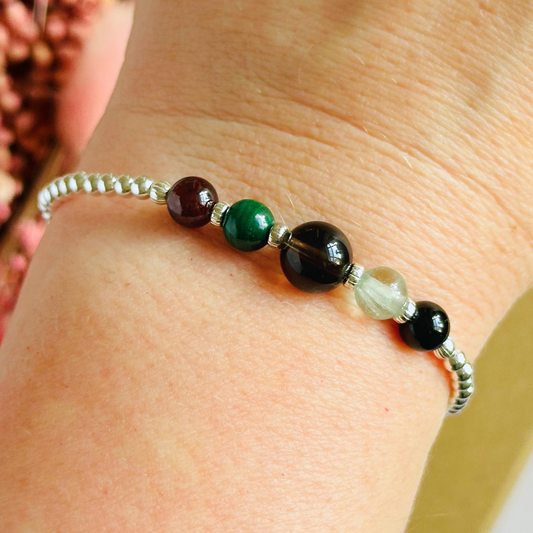 This sterling silver Capricorn bracelet is made with a selection of five healing crystals all believed to resonate with the Capricorn zodiac sign. The central bead is 8mm, the other four are 6mm. On an elasticated band of 3mm sterling silver beads with corrugated accent beads. Featuring garnet, malachite, fluorite, smoky quartz and black tourmaline.