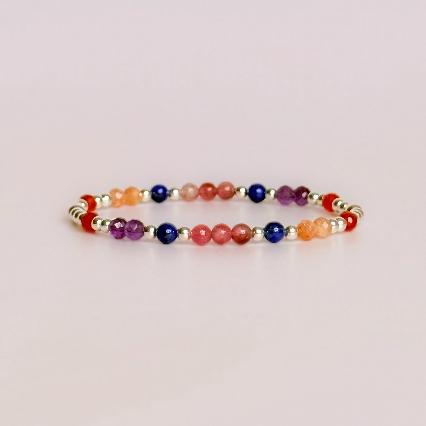 ‘Arabian Sunset' sterling silver dainty beaded bracelet with pink tourmaline, sunstone, carnelian, lapis lazuli and amethyst. Made with round 3mm sterling silver beads and 4mm smooth and faceted round crystal gemstone beads. Pictured against a pink background
