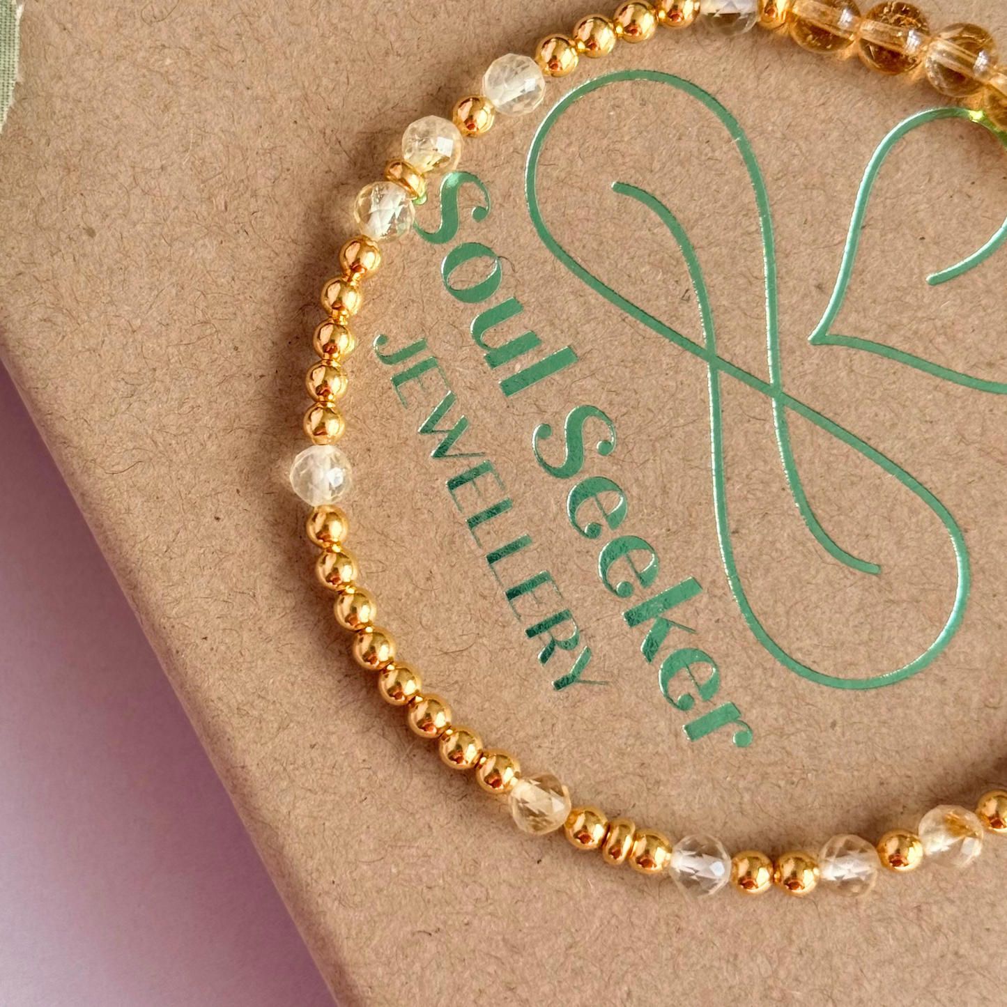 Citrine morse code bracelet that spells out the words ‘Ask, believe, receive’ in a combination of 4mm round smooth and faceted crystal beads with your choice of sterling silver or gold vermeil accent beads. Pictured in gold, close up on the box