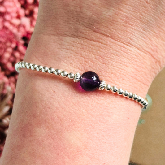 Sterling silver amethyst bracelet features an ethically mined 8mm amethyst bead, flanked by corrugated rondelle beads on a band of 3mm sterling silver beads. A bracelet to promote inner peace and calm.
