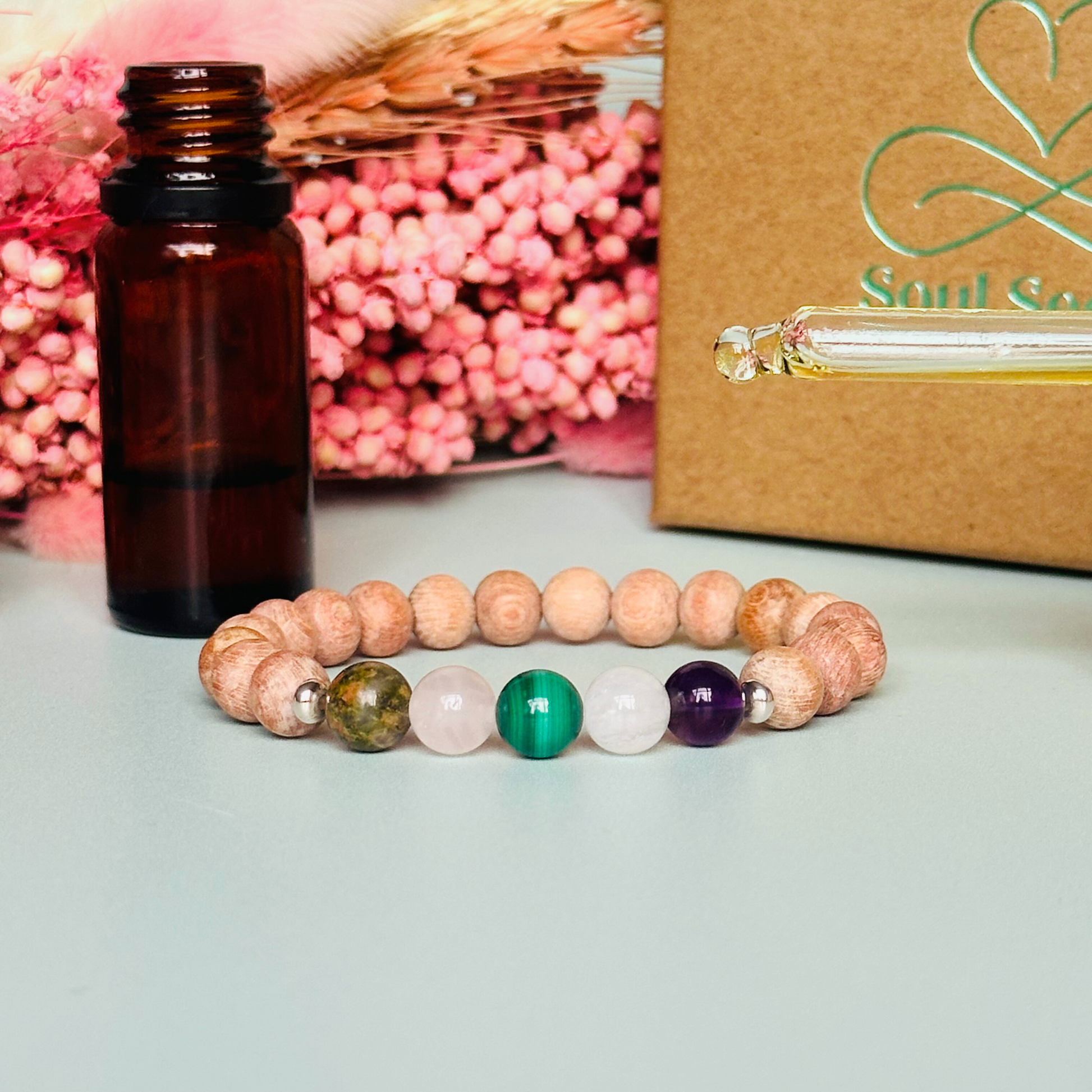 Essential oil diffuser bracelet featuring five crystal beads, all thought to aid in having a healthy pregnancy. Featuring unakite, rose quartz, amethyst, malachite and moonstne with raw rosewood beads that can act as a diffuser for essential oils.