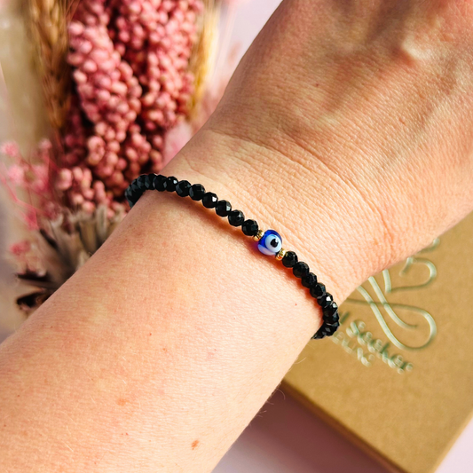 Dainty natural black tourmaline bracelet featuring ethically mined 4mm faceted gemstone beads, with a beautiful Turkish evil eye glass bead as the focal point. Choose from sterling silver or gold vermeil accent beads.