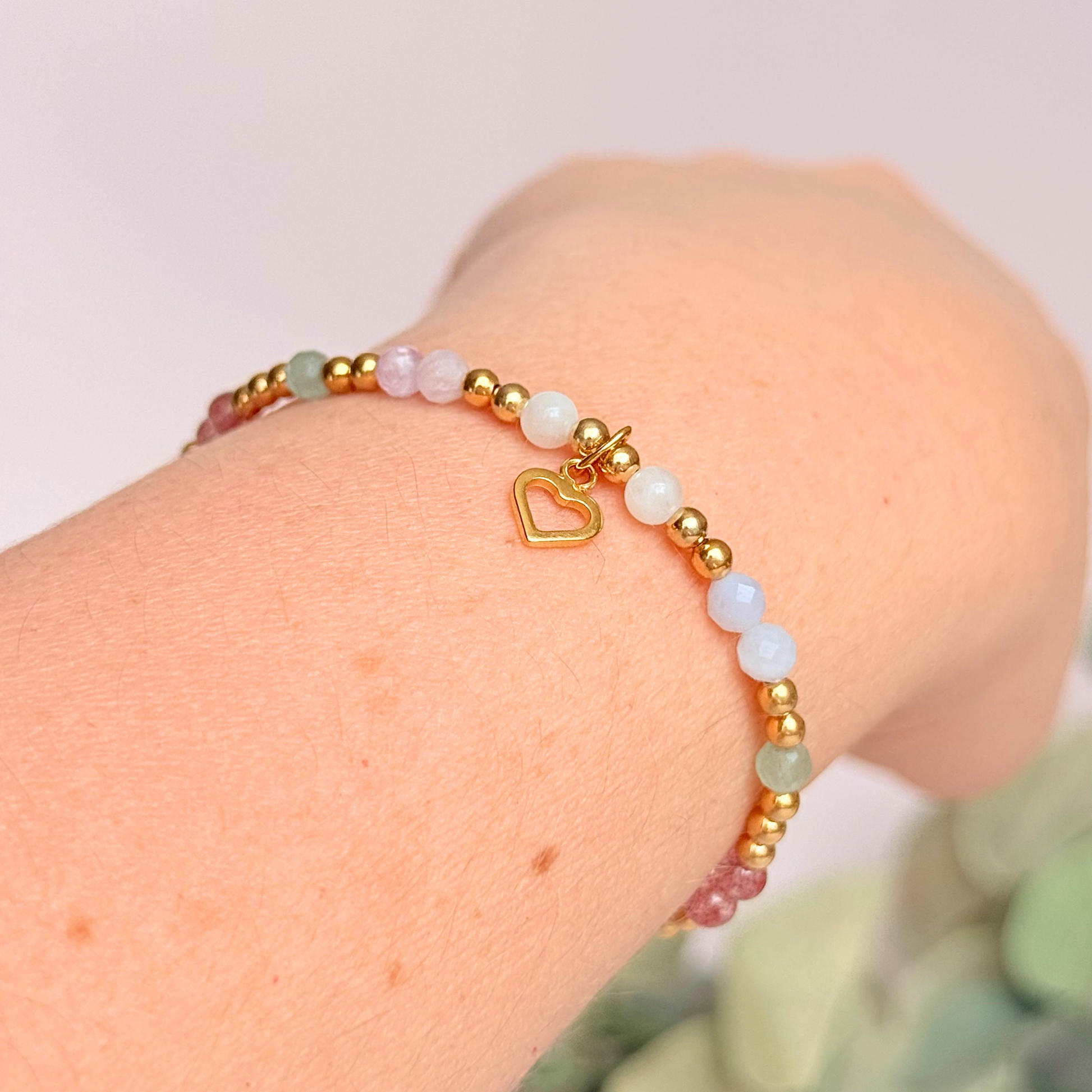'Soft girl summer' gold vermeil dainty beaded bracelet with Kunzite, moonstone, green aventurine, blue lace agate and strawberry quartz . With a beautiful open heart charm.Made with round 3mm gold vermeil beads and 4mm smooth and faceted round crystal gemstone beads. Pictured being worn, at an angle.