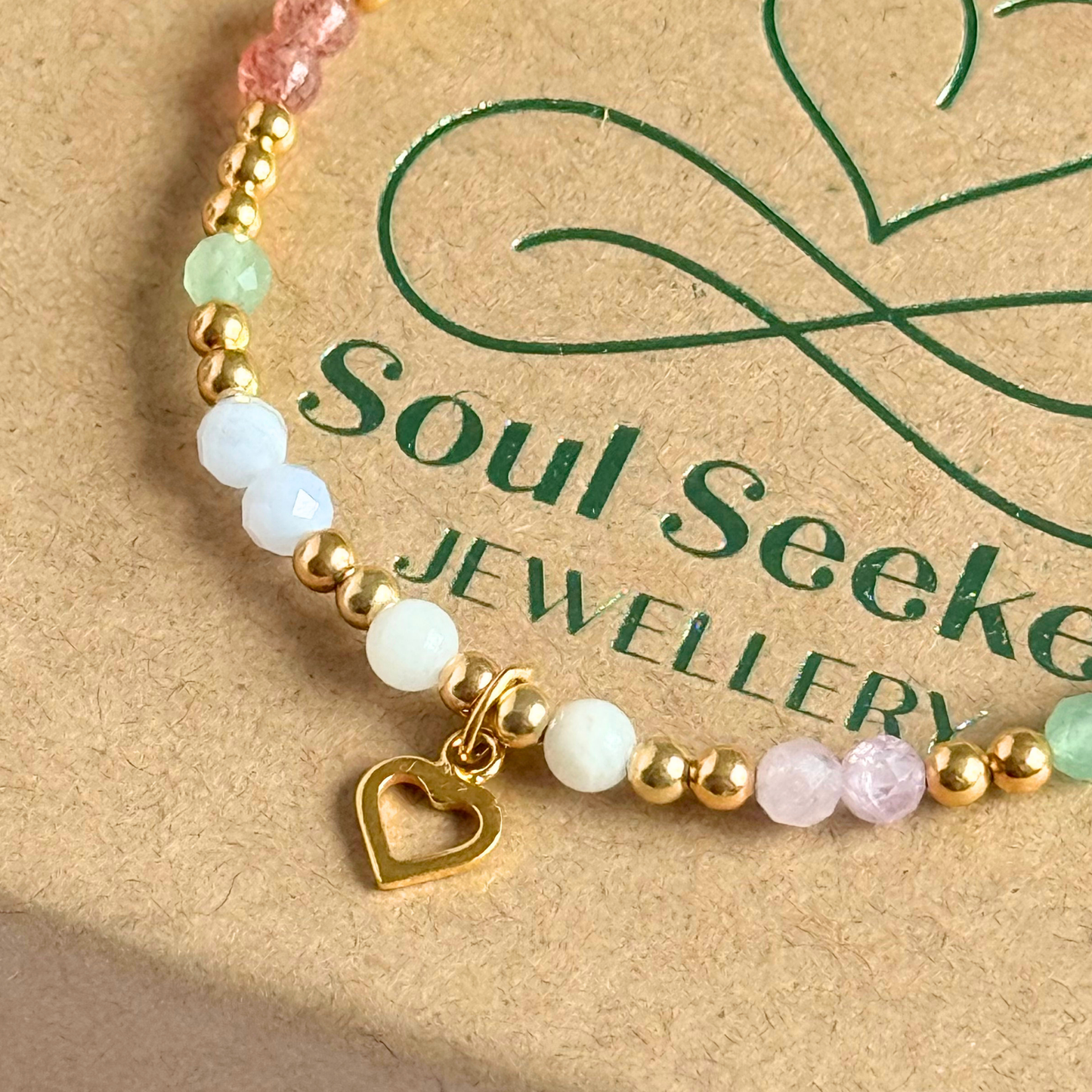 'Soft girl summer' gold vermeil dainty beaded bracelet with Kunzite, moonstone, green aventurine, blue lace agate and strawberry quartz . With a beautiful open heart charm.Made with round 3mm gold vermeil beads and 4mm smooth and faceted round crystal gemstone beads. Pictured close up, on top of the gift box