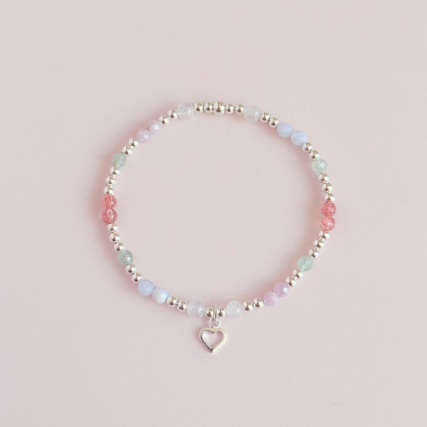 'Soft girl summer' sterling silver dainty beaded bracelet with Kunzite, moonstone, green aventurine, blue lace agate and strawberry quartz . With a beautiful open heart charm.Made with round 3mm sterling silver beads and 4mm smooth and faceted round crystal gemstone beads. Pictured from above, against a pink background