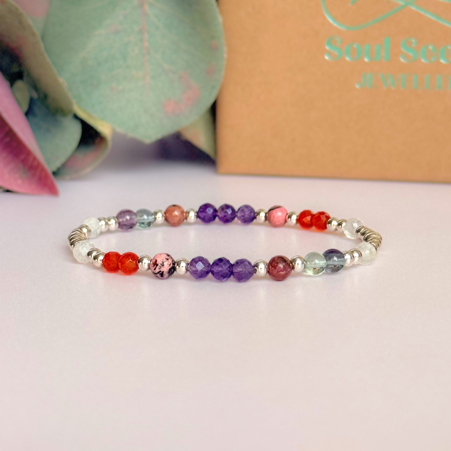 Dainty sterling silver crystal bracelet featuring five crystals, in 4mm faceted and smooth round style, each believed to help with perimenopause symptoms. Featuring amethyst, rhodonite, fluorite, moonstone and carnelian. Pictured in front of the gift box.