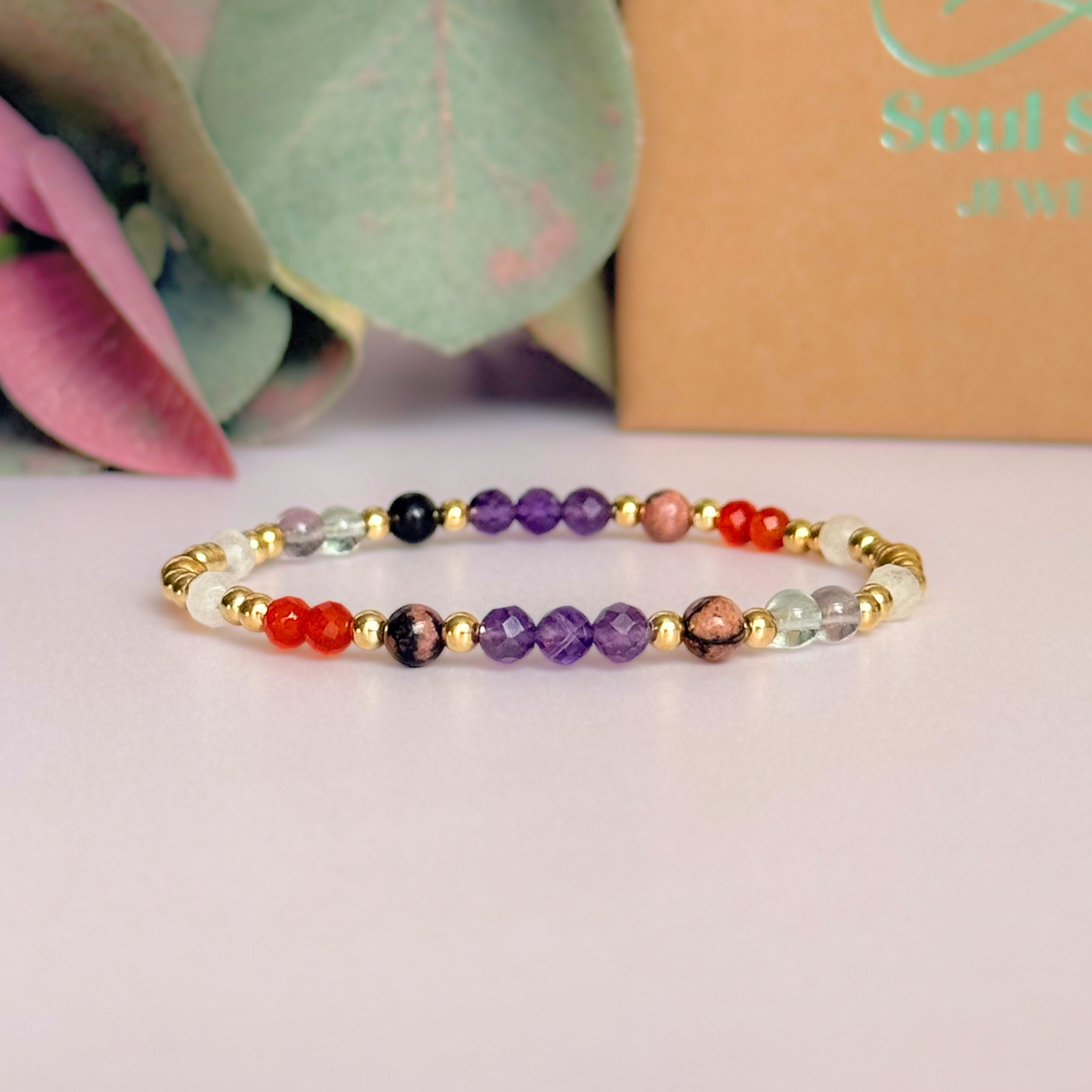 Dainty gold vermeil crystal bracelet featuring five crystals, in 4mm faceted and smooth round style, each believed to help with perimenopause symptoms. Featuring amethyst, rhodonite, fluorite, moonstone and carnelian. Pictured in front of the gift box.