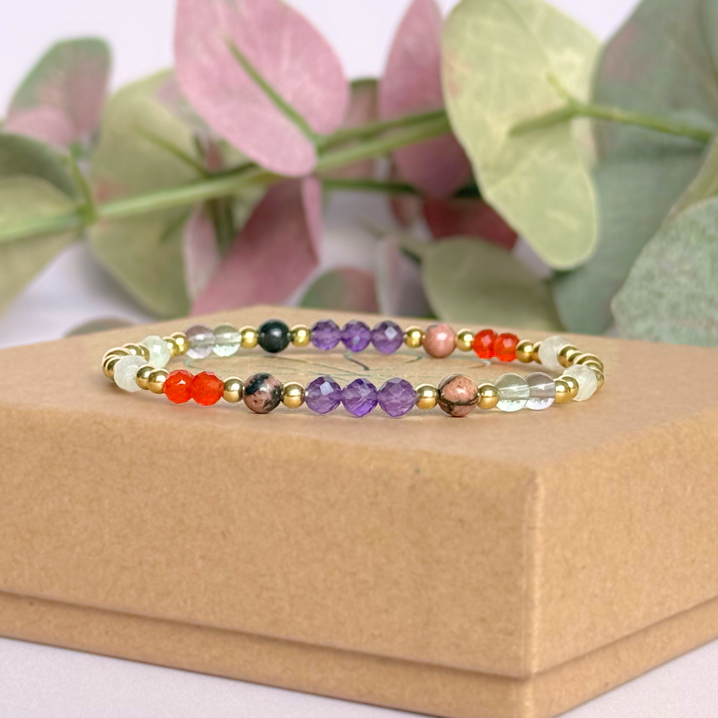 Dainty gold vermeil crystal bracelet featuring five crystals, in 4mm faceted and smooth round style, each believed to help with perimenopause symptoms. Featuring amethyst, rhodonite, fluorite, moonstone and carnelian. Pictured on top of the gift box.