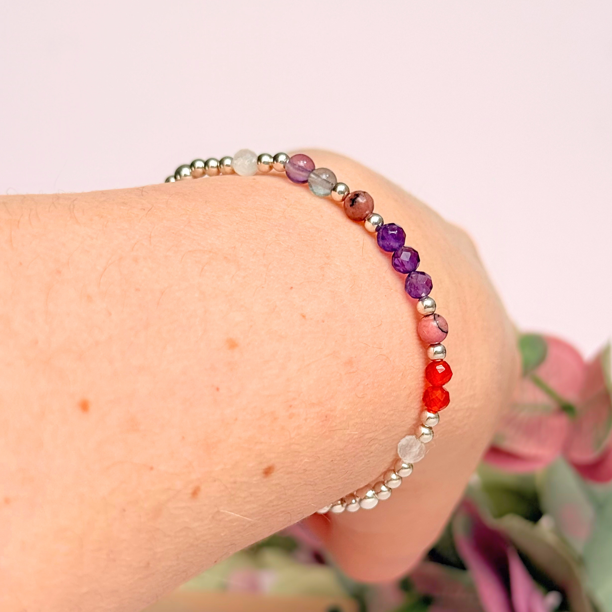 Dainty sterling silver crystal bracelet featuring five crystals, in 4mm faceted and smooth round style, each believed to help with perimenopause symptoms. Featuring amethyst, rhodonite, fluorite, moonstone and carnelian. Pictured being worn, on an angle.
