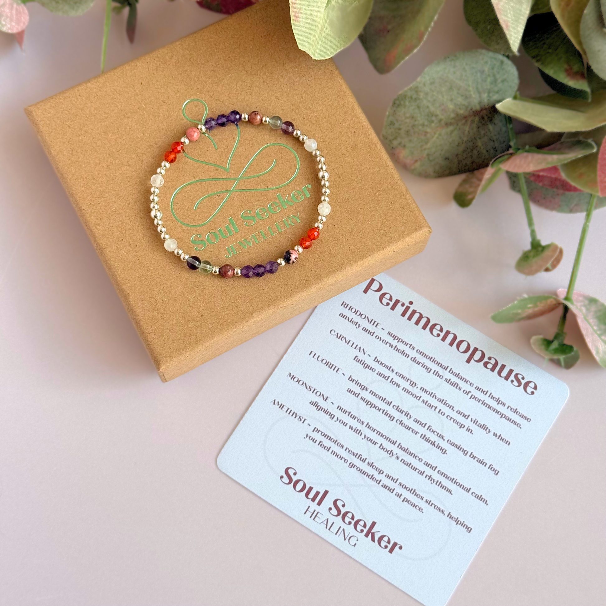 Dainty sterling silver crystal bracelet featuring five crystals, in 4mm faceted and smooth round style, each believed to help with perimenopause symptoms. Featuring amethyst, rhodonite, fluorite, moonstone and carnelian. Pictured on top of the gift box, with the crystal information card.