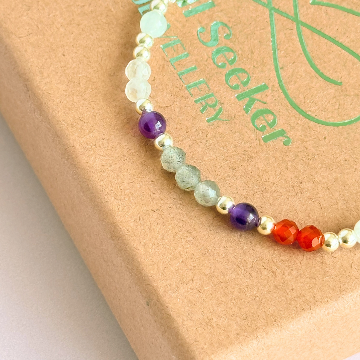 Dainty sterling silver crystal bracelet featuring five crystals, in 4mm faceted and smooth round style, each believed to help with hormonal balance. Featuring amethyst, moonstone, carnelian, labradorite and rose quartz. Close up on top of the gift box.