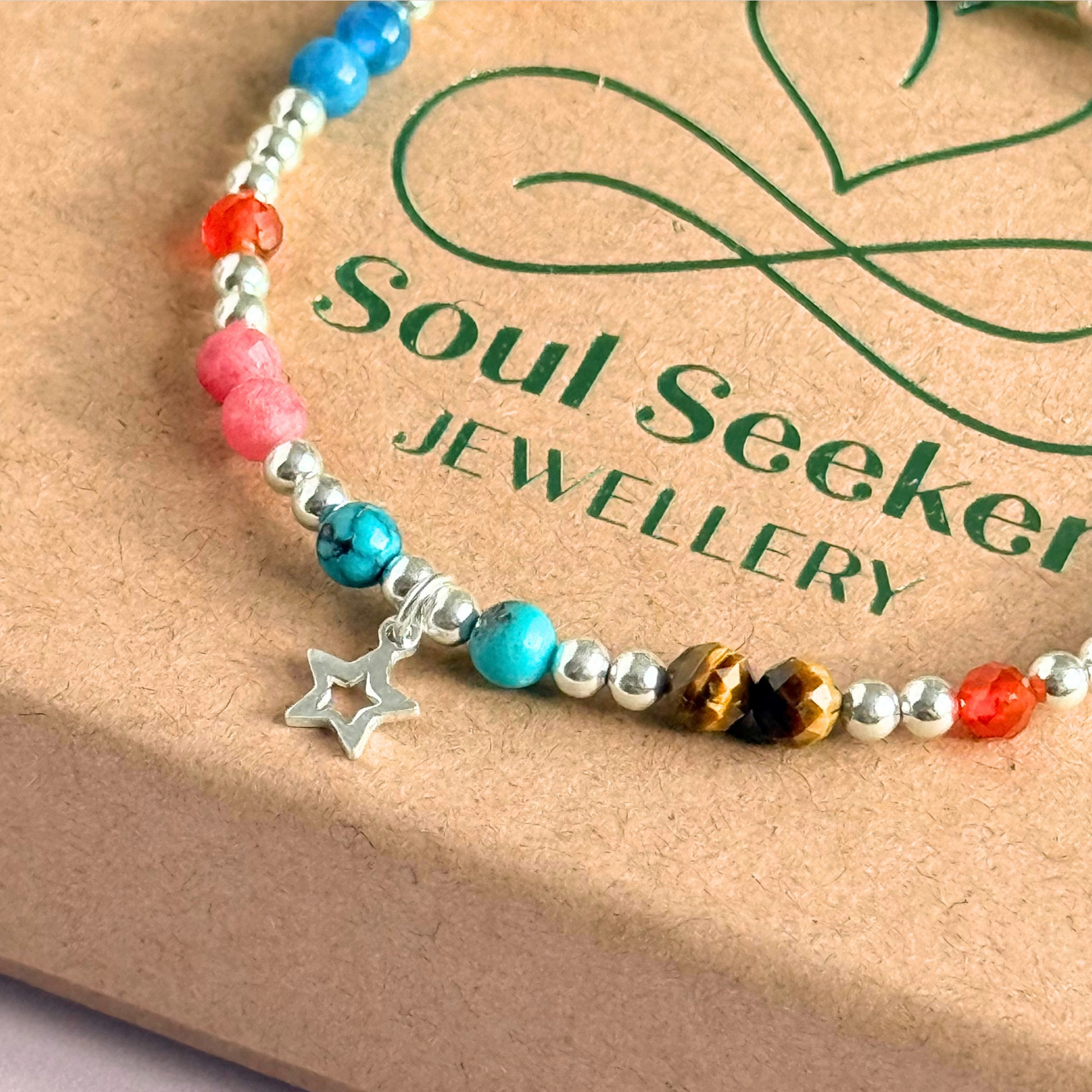 'Hot girl summer' sterling silver dainty beaded bracelet with tigers eye, turquoise, apatite, carnelian and rhodochrosite. With a beautiful open star charm. Made with round 3mm sterling silver beads and 4mm smooth and faceted round crystal gemstone beads. Pictured close up, on top of the gift box.
