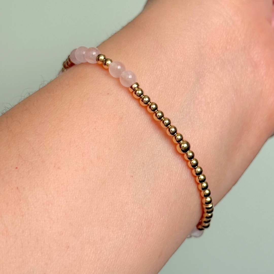 Morse code secret message bracelet spelling out the words Mum est. 2025 in gold filled and rose quartz crystal beads. elasticated with 4mm rose quartz beads and 3mm gold filled beads.