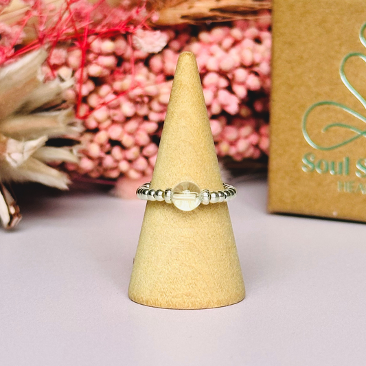 This sterling silver clear quartz ring features a 6mm round ethically sourced clear quartz bead, surrounded by sterling silver corrugated rondelle beads and delicate 2.5mm sterling silver beads. April birthstone.

