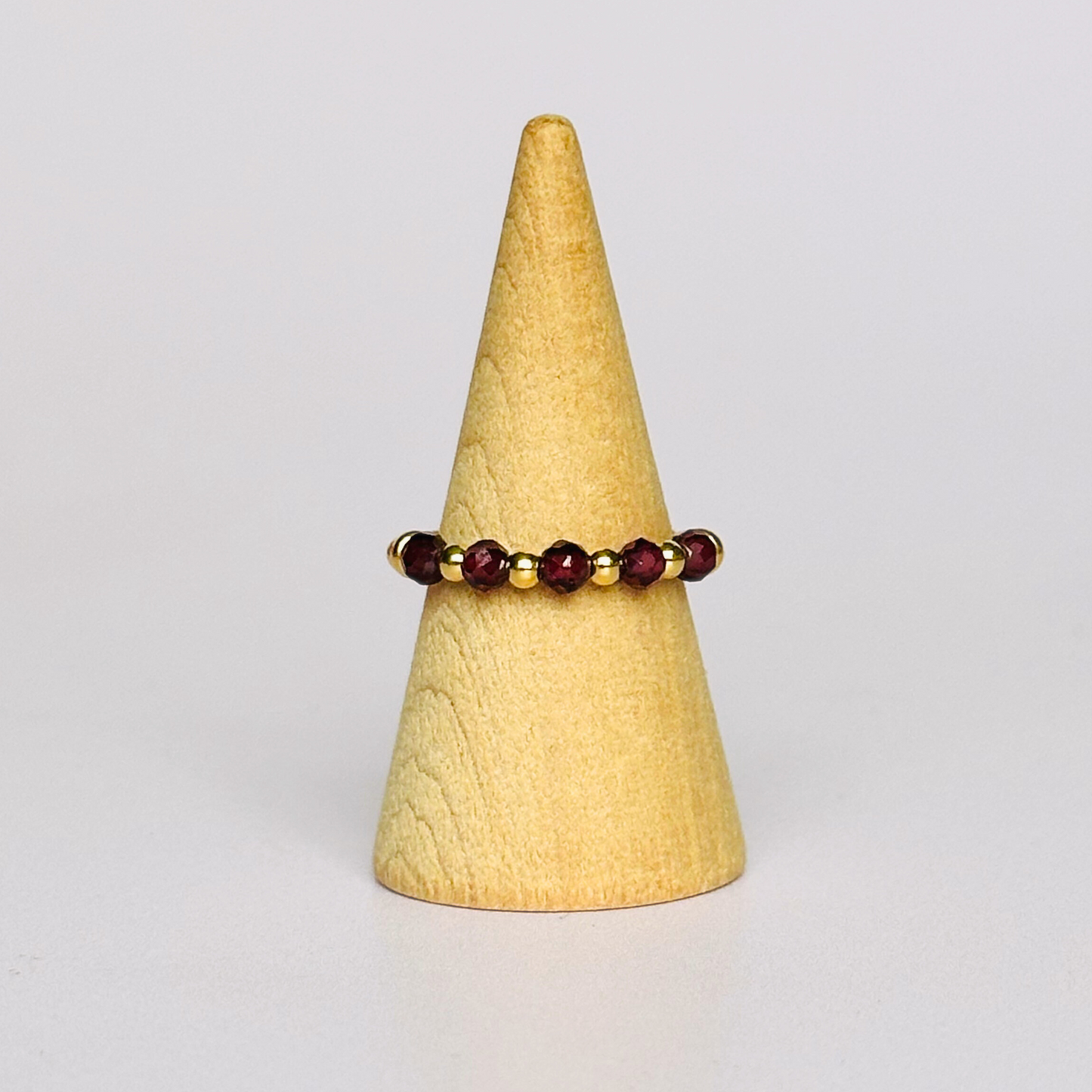 Gold vermeil garnet ring featuring five 3mm faceted round garnet beads on a elasticated ring band of 2.5mm gold vermeil beads.