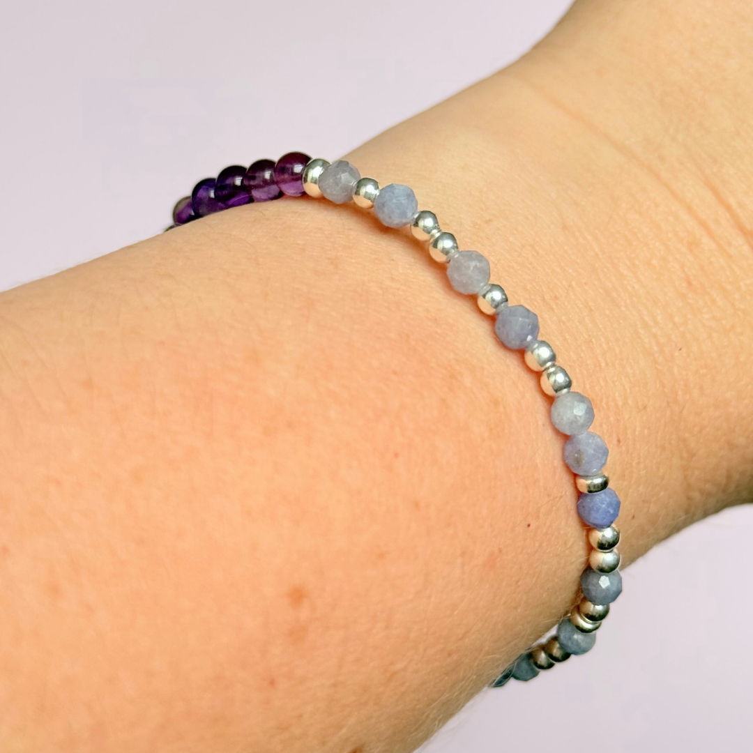 Amethyst and tanzanite elasticated stretch crystal morse code bracelet that spells out the words ‘Calm TF down’ in a combination of 4mm round amethyst beads, 4mm faceted tanzanite beads and either sterling silver or gold vermeil 3mm round beads. The words start and end at the rondelle spacer beads.