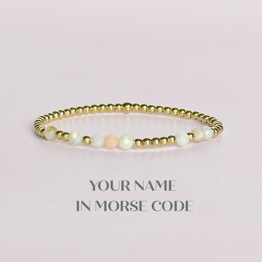 Morse code secret message bracelet spelling out your chosen name in gold filled and pink opal crystal beads. Elasticated with 4mm faceted pink opal beads and 3mm gold filled beads. Custom October birthstone bracelet.