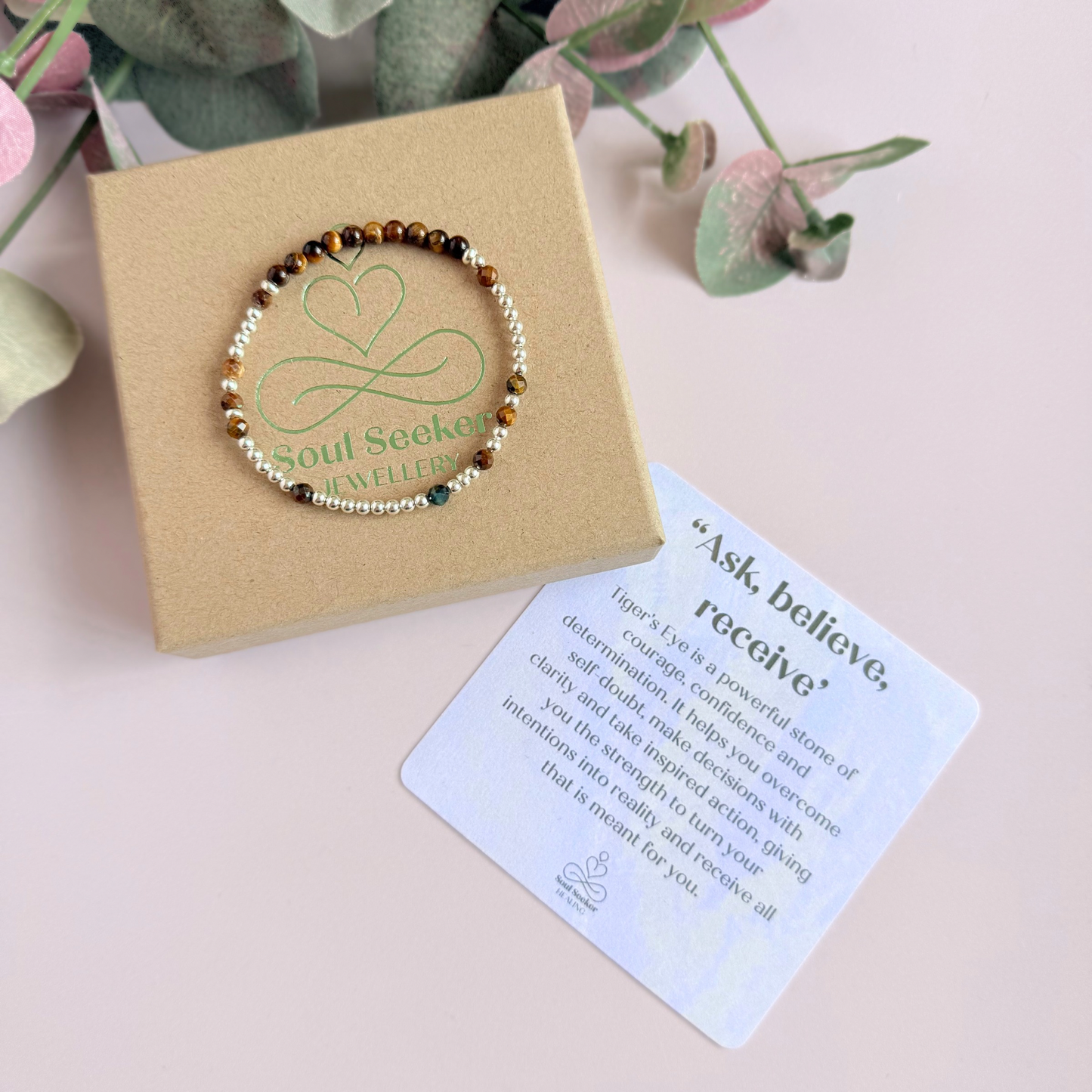 Tigers eye morse code bracelet that spells out the words ‘Ask, believe, receive’ in a combination of 4mm round smooth and faceted crystal beads with your choice of sterling silver or gold vermeil accent beads. Pictured in silver, on the box with the crystal information card