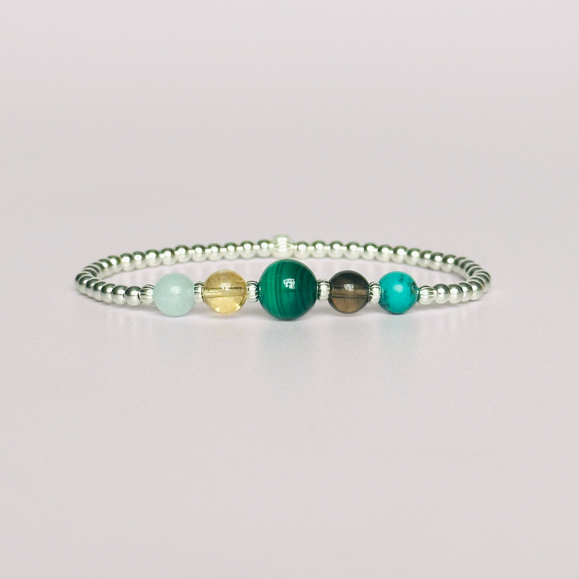 This sterling silver Scorpio bracelet is made with a selection of five healing crystals all believed to resonate with the Scorpio zodiac sign. The central bead is 8mm, the other four are 6mm. On an elasticated band of 3mm sterling silver beads with corrugated accent beads. Featuring aquamarine, citrine, malachite, smoky quartz and turquoise.