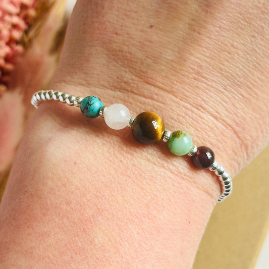 This sterling silver Leo bracelet is made with a selection of five healing crystals all believed to resonate with the Leo zodiac sign. The central bead is 8mm, the other four are 6mm. On an elasticated band of 3mm sterling silver beads with corrugated accent beads. Featuring chrysocolla, garnet, tigers eye, rose quartz and turquoise.