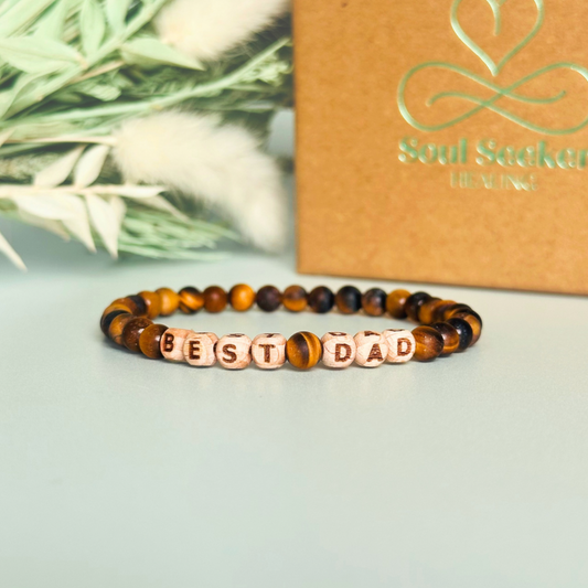 Men’s crystal bracelet with 6mm frosted tigers eye gemstone crystal beads and laser engraved wooden letter beads featuring the words best dad or can also be made with any other words or letters.