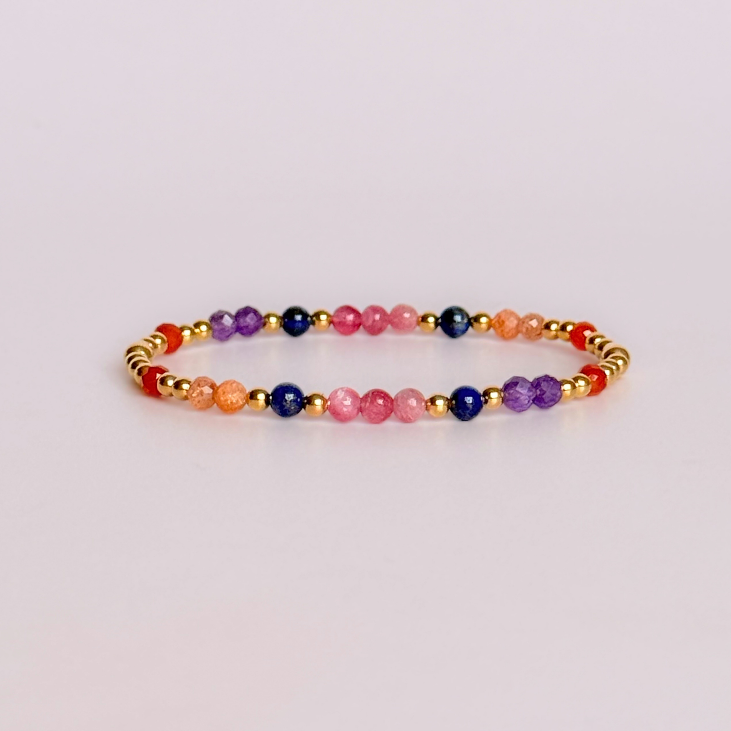‘Arabian Sunset' gold vermeil dainty beaded bracelet with pink tourmaline, sunstone, carnelian, lapis lazuli and amethyst. Made with round 3mm gold vermeil beads and 4mm smooth and faceted round crystal gemstone beads. Pictured against a pink background