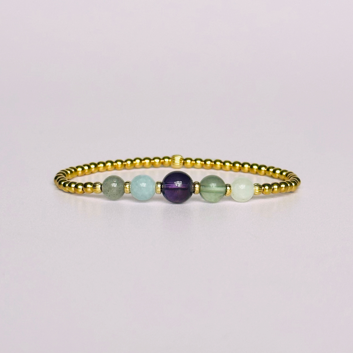 This gold vermeil Aquarius bracelet is made with a selection of five healing crystals all believed to resonate with the Aquarius zodiac sign. The central bead is 8mm, the other four are 6mm. On an elasticated band of 3mm gold vermeil beads with corrugated accent beads. Featuring labradorite, moonstone, fluorite, amethyst and aquamarine.