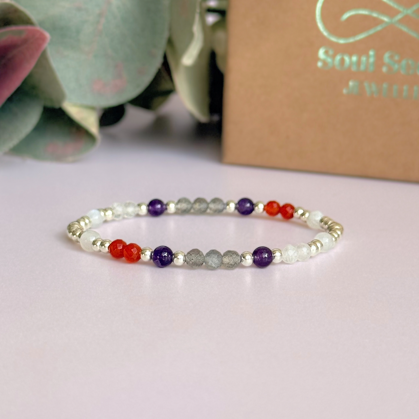 Dainty sterling silver crystal bracelet featuring five crystals, in 4mm faceted and smooth round style, each believed to help with hormonal balance. Featuring amethyst, moonstone, carnelian, labradorite and rose quartz. Pictured in front of the gift box.