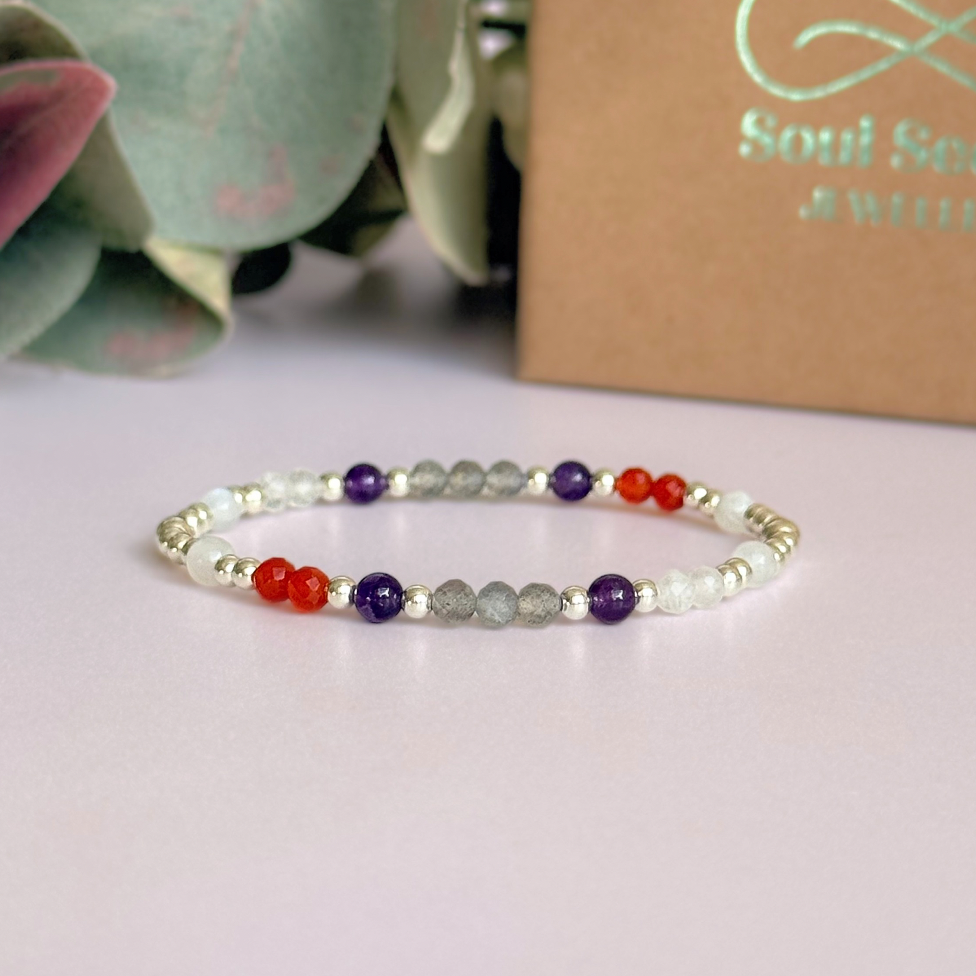 Dainty sterling silver crystal bracelet featuring five crystals, in 4mm faceted and smooth round style, each believed to help with hormonal balance. Featuring amethyst, moonstone, carnelian, labradorite and rose quartz. Pictured in front of the gift box.