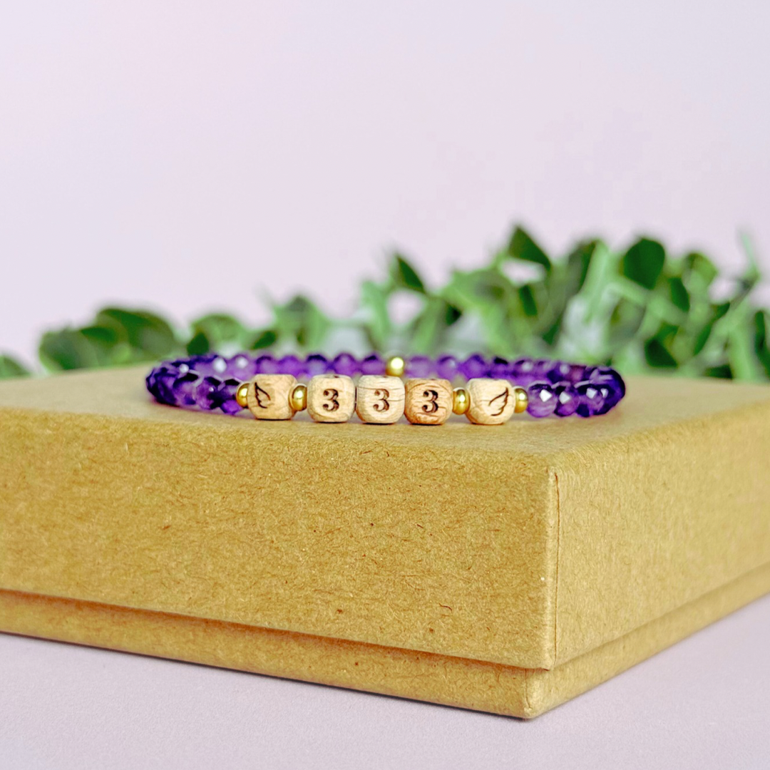 Bracelet featuring engraved wooden 333 angel number and wing beads, on the band of 4mm faceted amethyst round crystal gemstone beads. Finished with your choice of gold vermeil, sterling silver or rose gold vermeil accent beads.