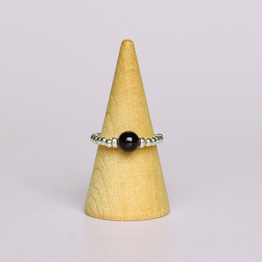 Sterling silver garnet ring featuring a 6mm smooth round garnet bead on a elasticated ring band of 2.5mm sterling silver beads.