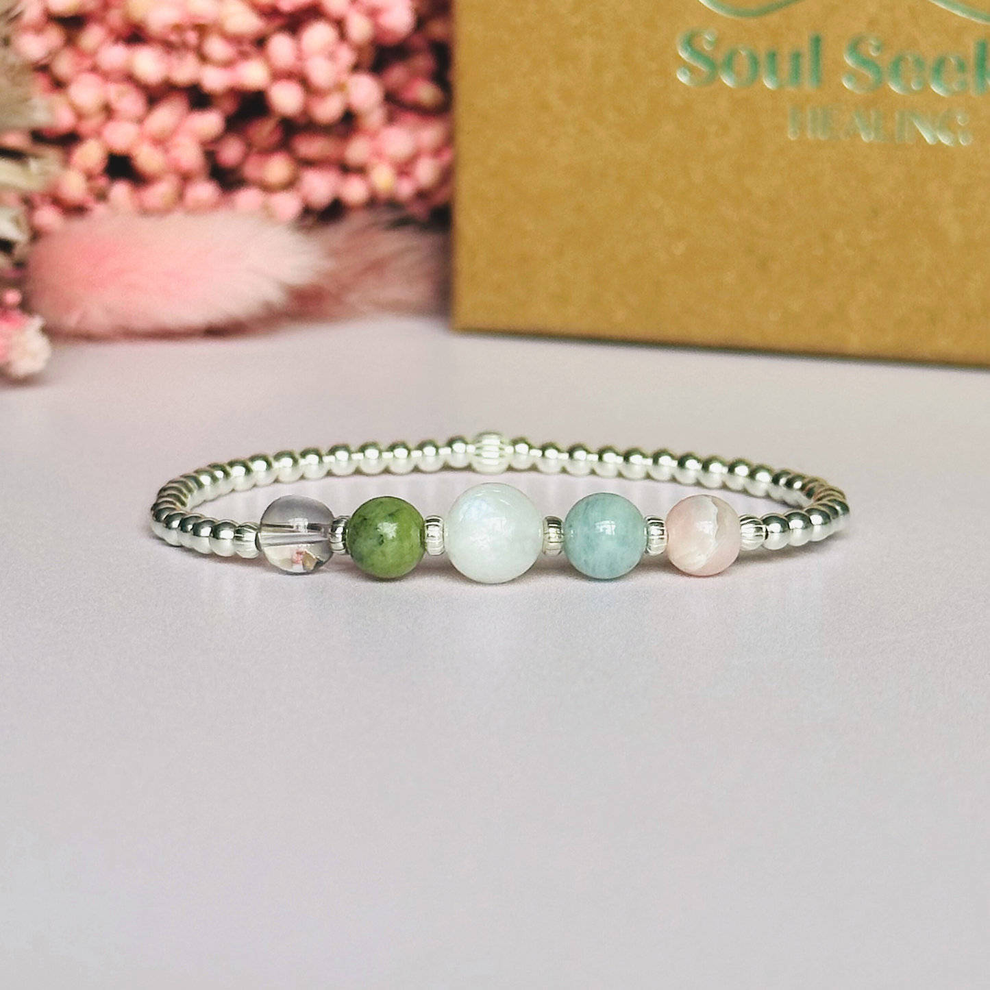 This sterling silver Libra bracelet is made with a selection of five healing crystals all believed to resonate with the Libra zodiac sign. The central bead is 8mm, the other four are 6mm. On an elasticated band of 3mm sterling silver beads with corrugated accent beads. Featuring ametrine, jade, moonstone, aquamarine and pink opal.