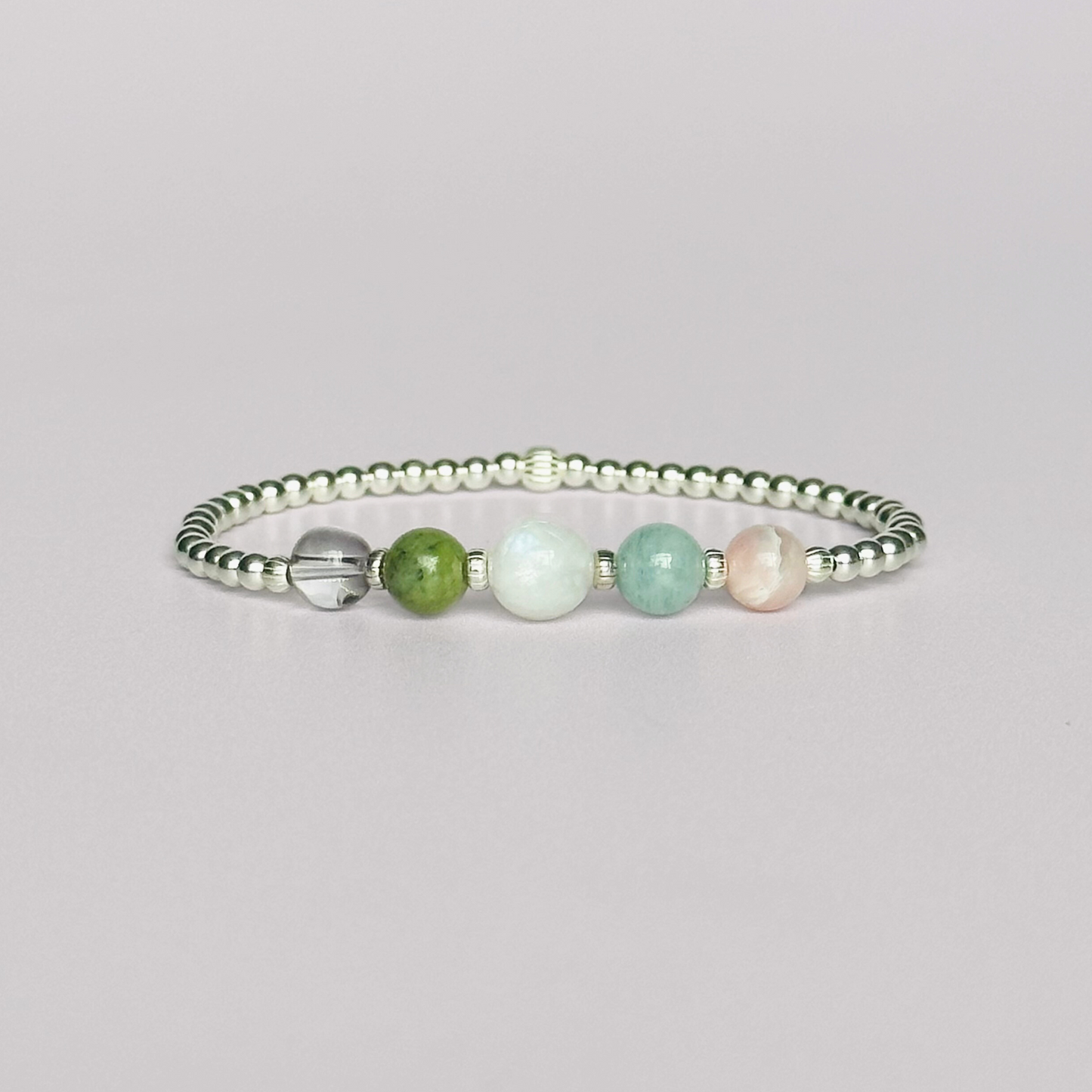 This sterling silver Libra bracelet is made with a selection of five healing crystals all believed to resonate with the Libra zodiac sign. The central bead is 8mm, the other four are 6mm. On an elasticated band of 3mm sterling silver beads with corrugated accent beads. Featuring ametrine, jade, moonstone, aquamarine and pink opal.