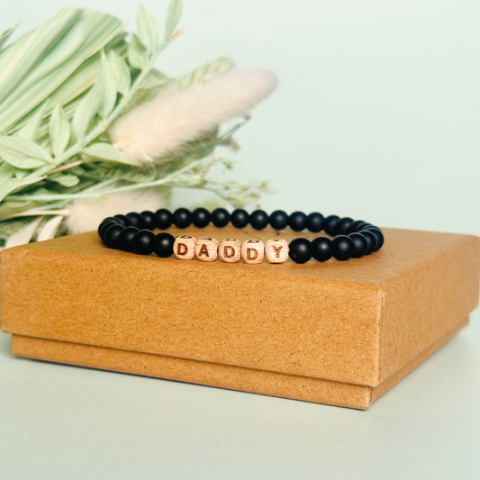Men’s crystal bracelet with 6mm frosted black onyx gemstone crystal beads and laser engraved wooden letter beads featuring the word daddy or can also be made with any other words or letters.