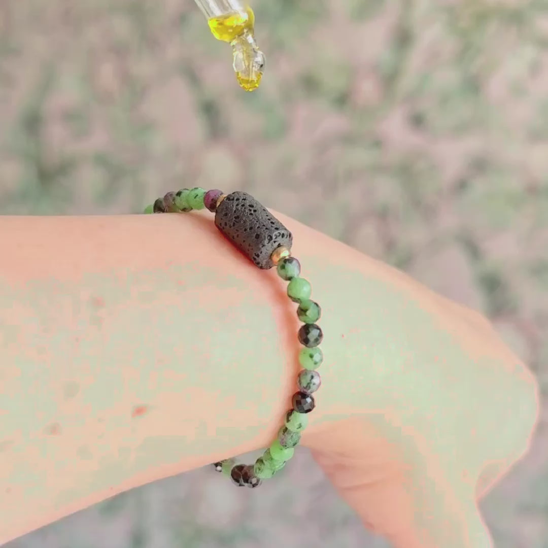 Essential oil diffuser bracelet featuring black lava rock tube bead on the band of 4mm faceted ruby in zoisite beads. Finished with your choice of sterling silver or gold vermeil accent beads.