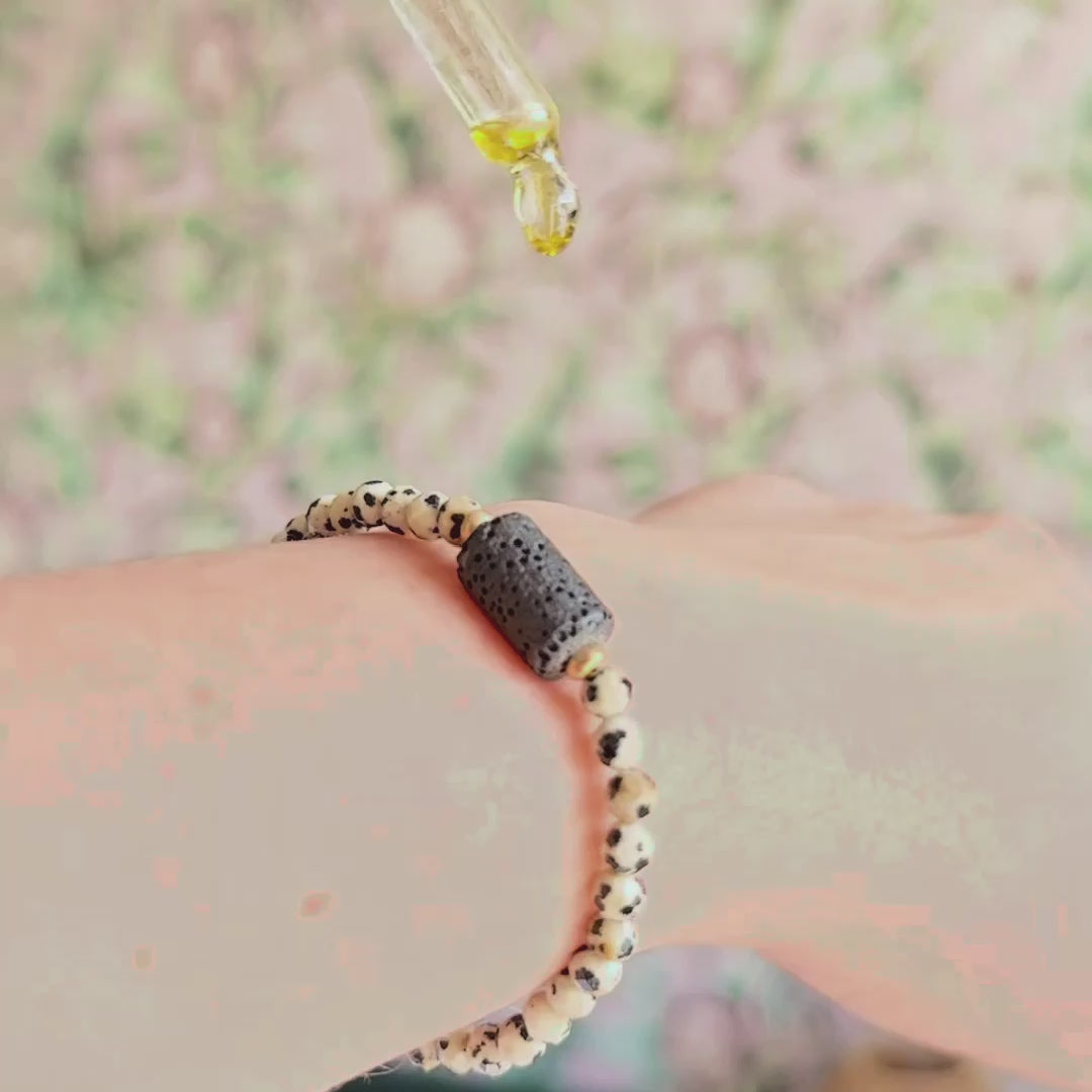 Essential oil diffuser bracelet featuring black lava rock tube bead on the band of 4mm faceted dalmatian jasper beads. Finished with your choice of sterling silver or gold vermeil accent beads.